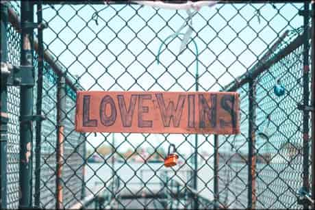 chainlink fence with words that say love wins