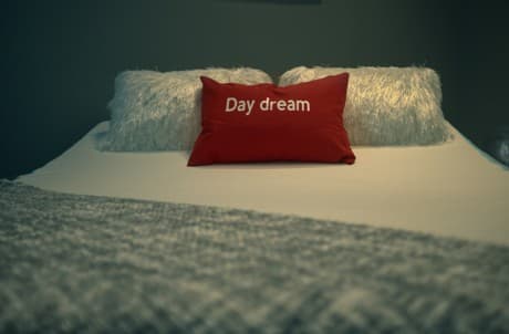 Inspirational Picture picture of a pliiow on a bed with the words daydream on it.