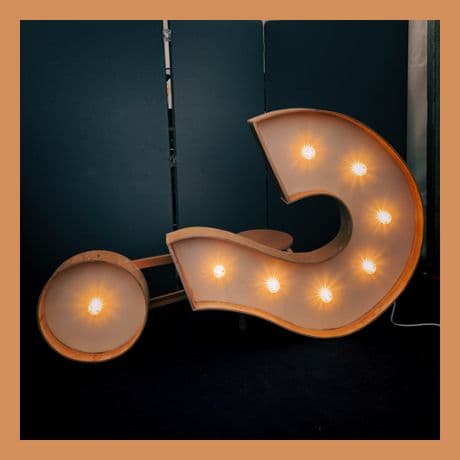 Inspirational Picture question mark lit up and hanging on its side.