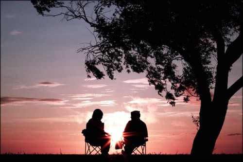 two people siitng together at sunset